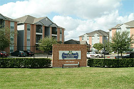 The brick apartment buildings and landscaped entrance at Plaza De Magnolia